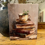 Teacup atop vintage books canvas art print
